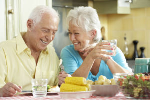 dental implant patients smiling together at the dinner table because they went to a dental implant center